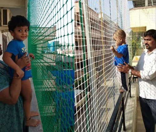 Family on a balcony with green and white safety nets fitted along the railing